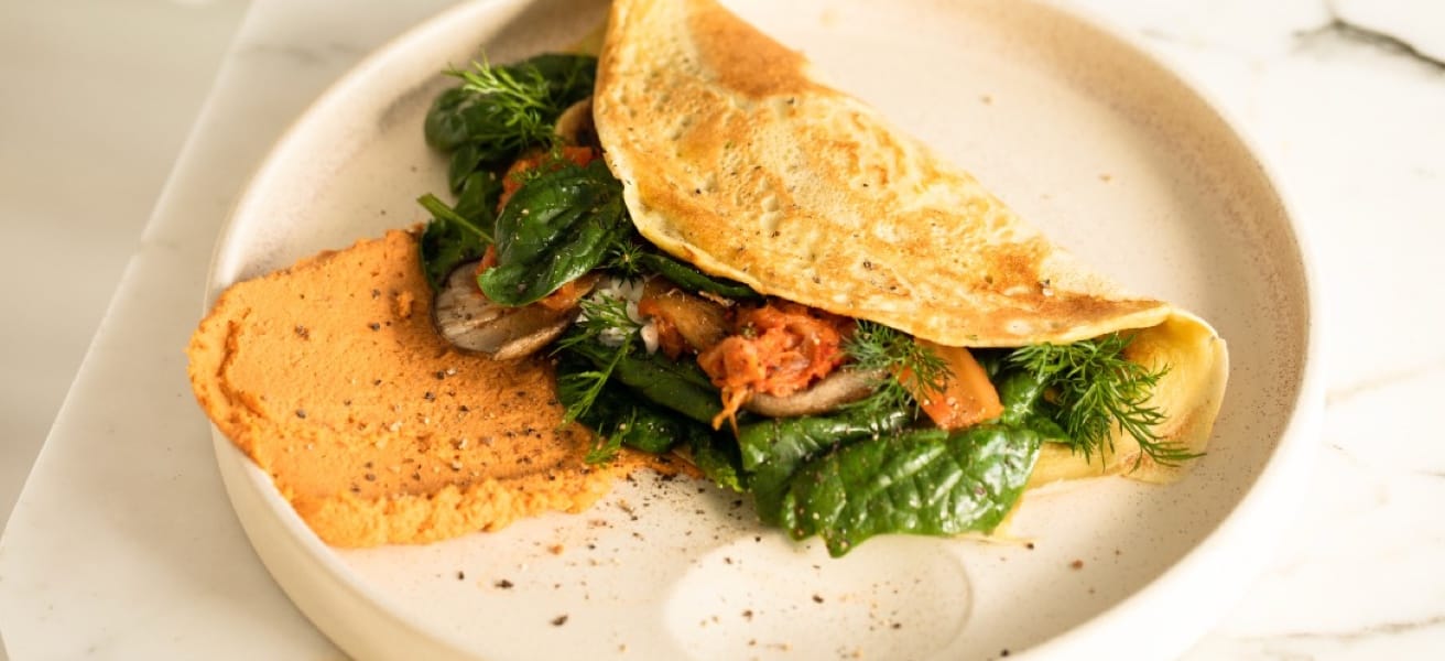 Une assiette composée d'une omelette moelleuse accompagnée d'un assortiment coloré de légumes frais.